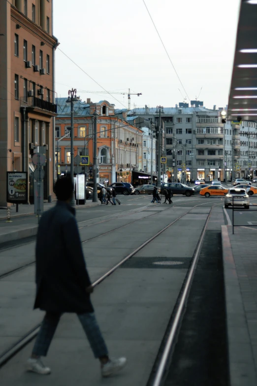 a man walking down a train track with cars on both sides