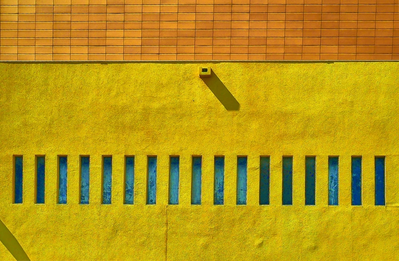 an orange and blue brick wall next to a street