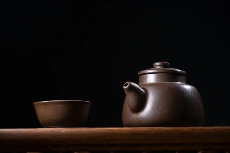 two brown cups sit next to a teapot