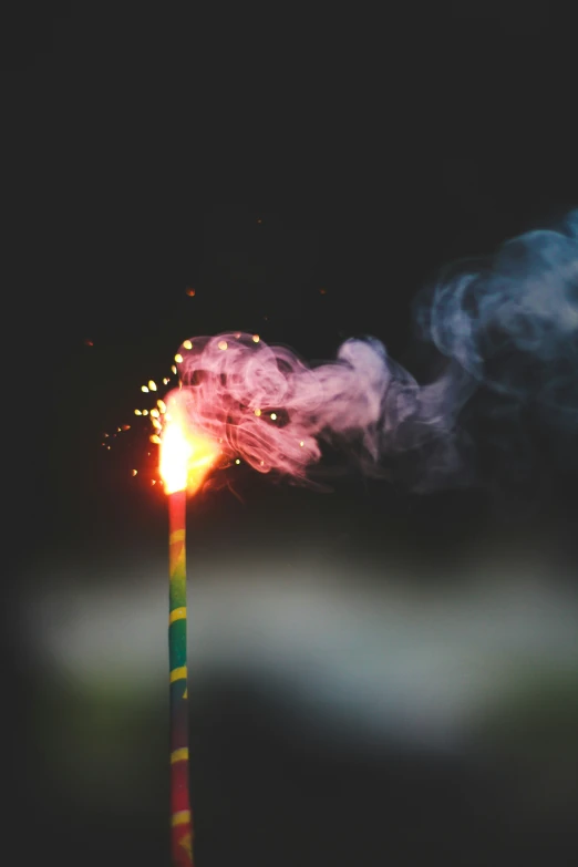 the brightly lit sparkler has lots of red and yellow smoke