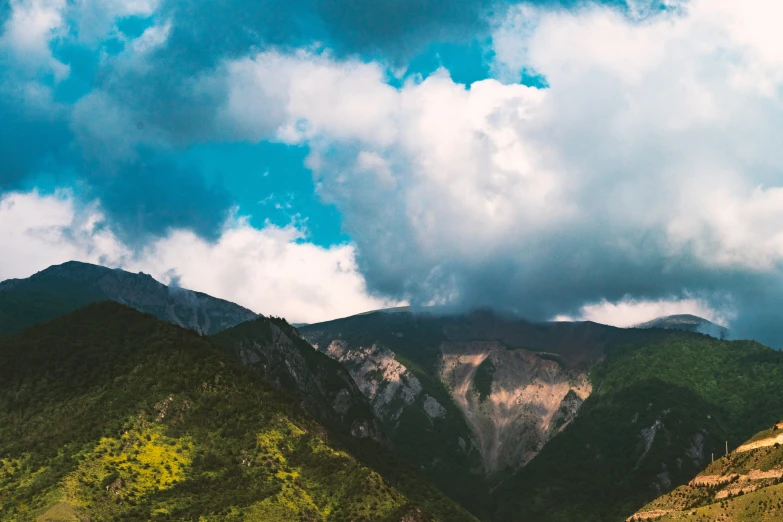 a horse stands in the mountains under some clouds