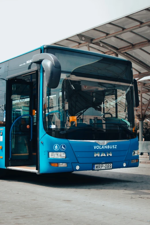 a blue bus is parked next to an awning