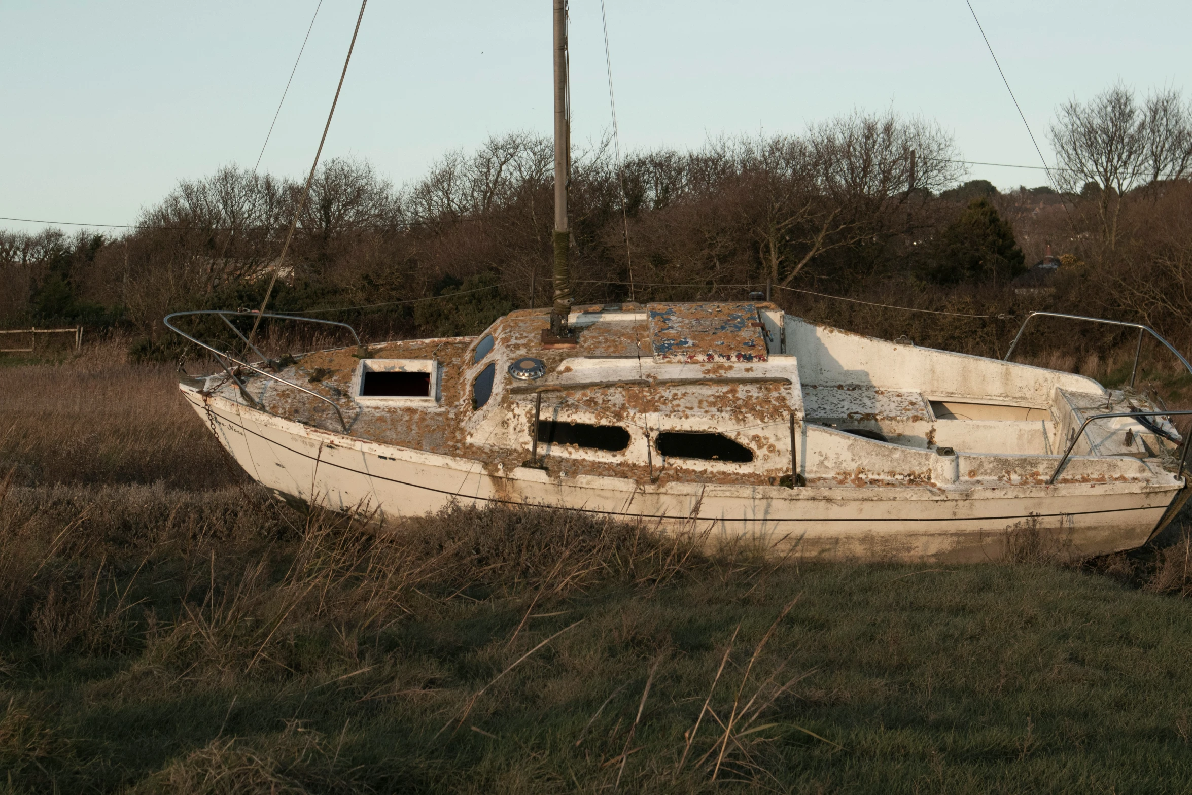 an old abandoned sail boat is sitting on the field