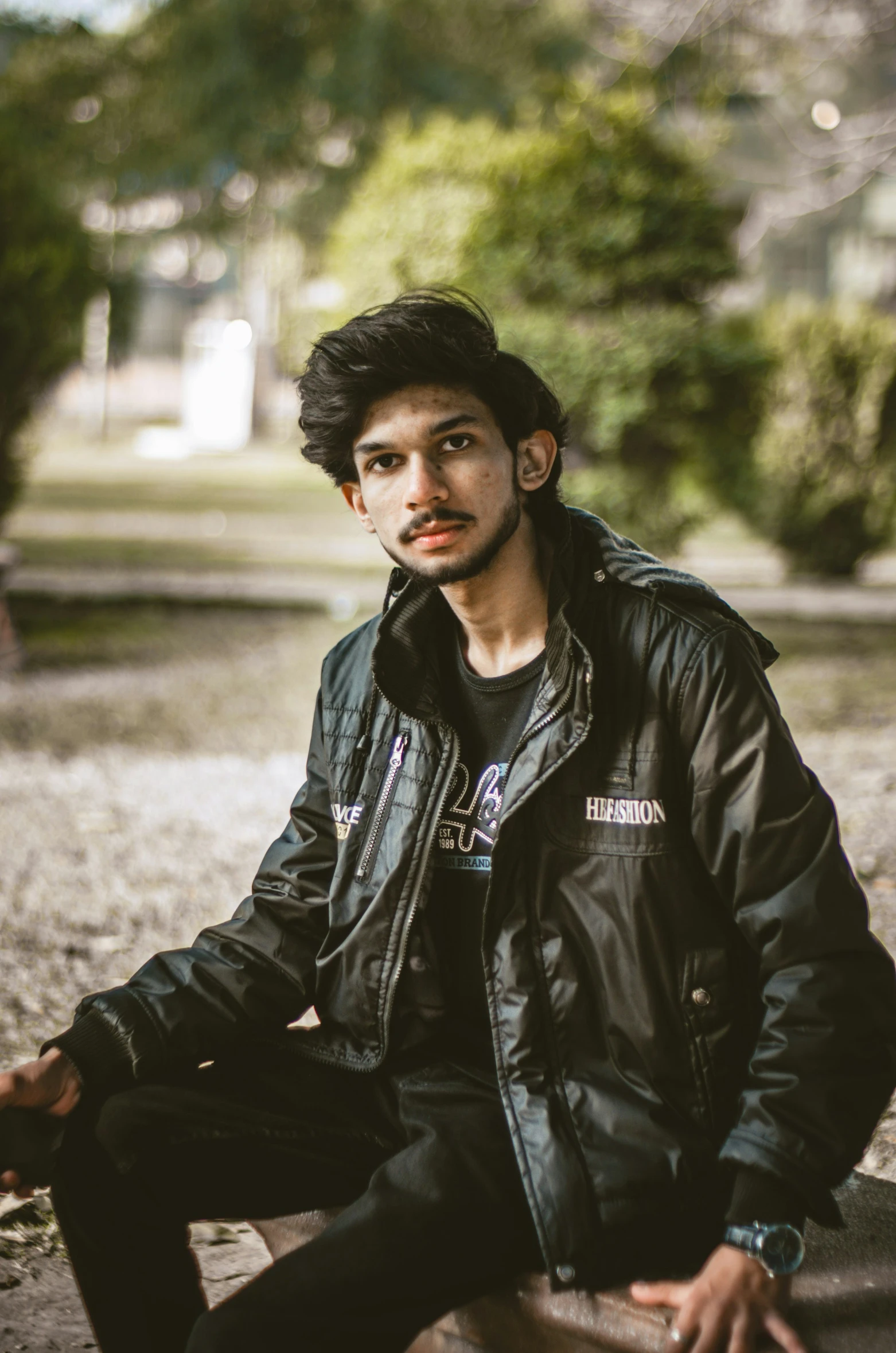 a young man sitting on a skateboard in a park