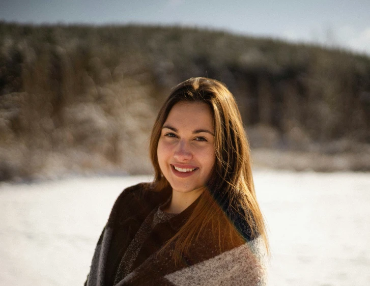 a girl is holding up her blanket on a snowy day