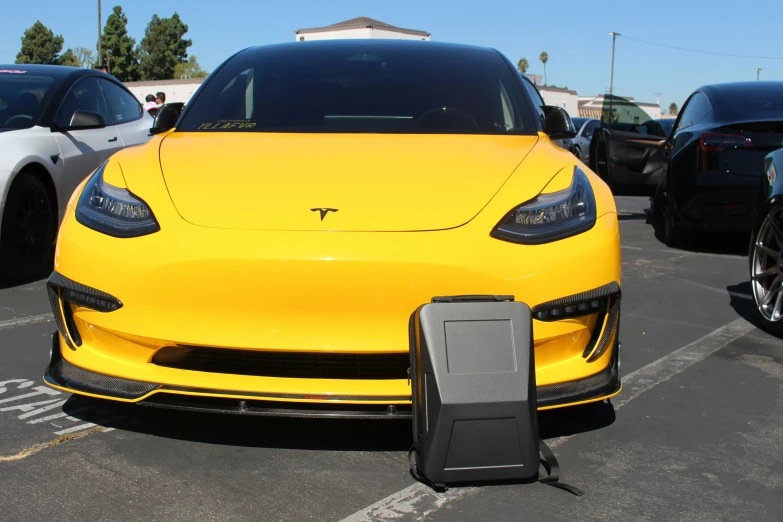 a yellow tesla sports utility vehicle parked in a parking lot