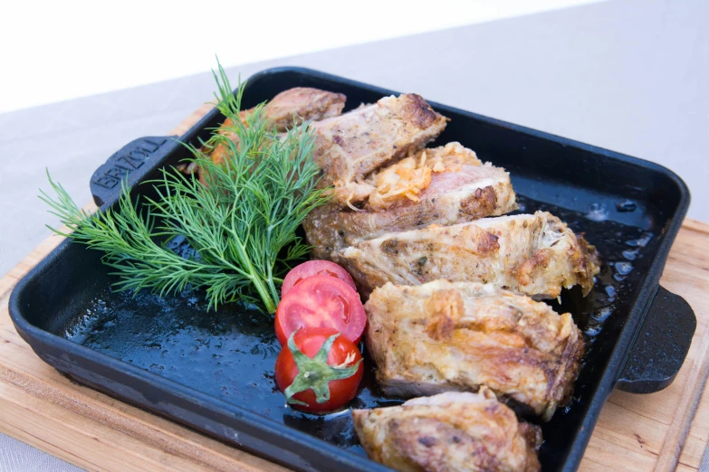 a square pan of food with meat and herbs
