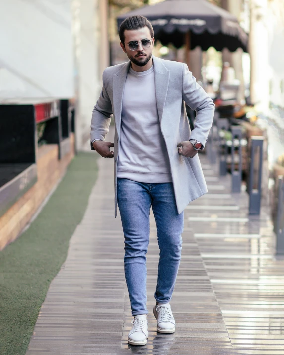 man with gray coat and sunglasses walking in a city