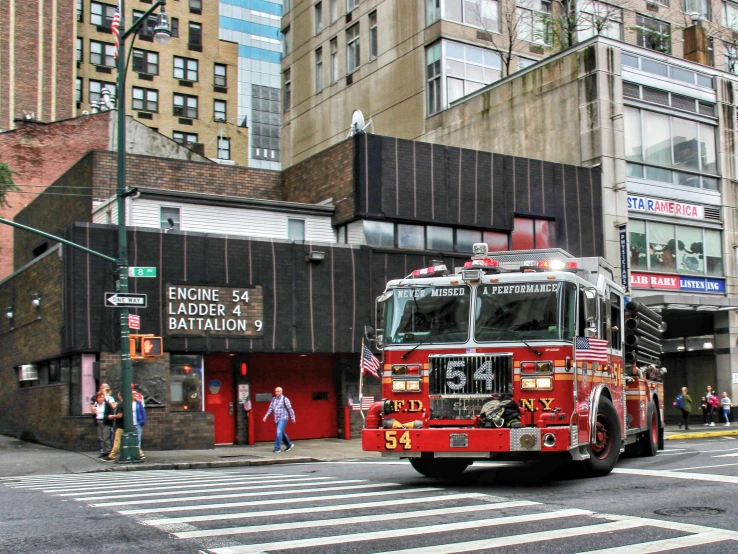 a red fire truck driving down a street near tall buildings