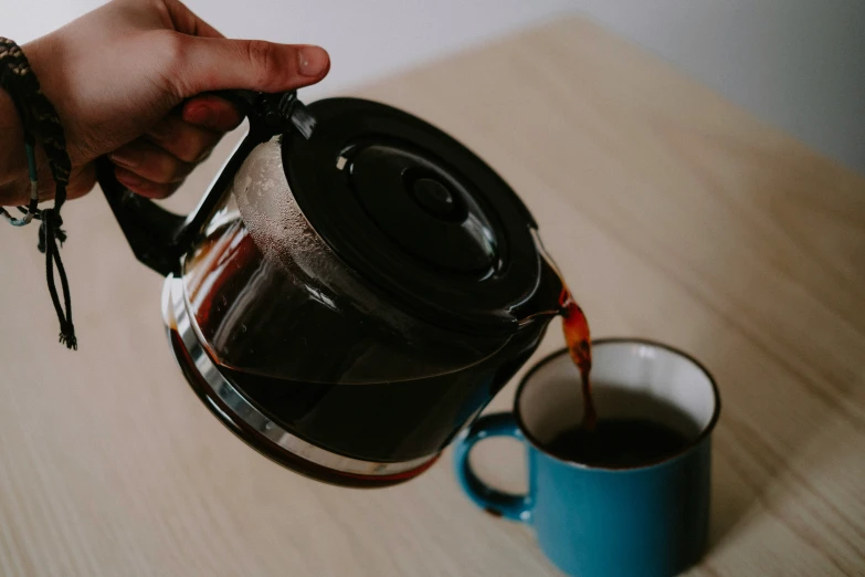 a person pouring coffee out from a cup