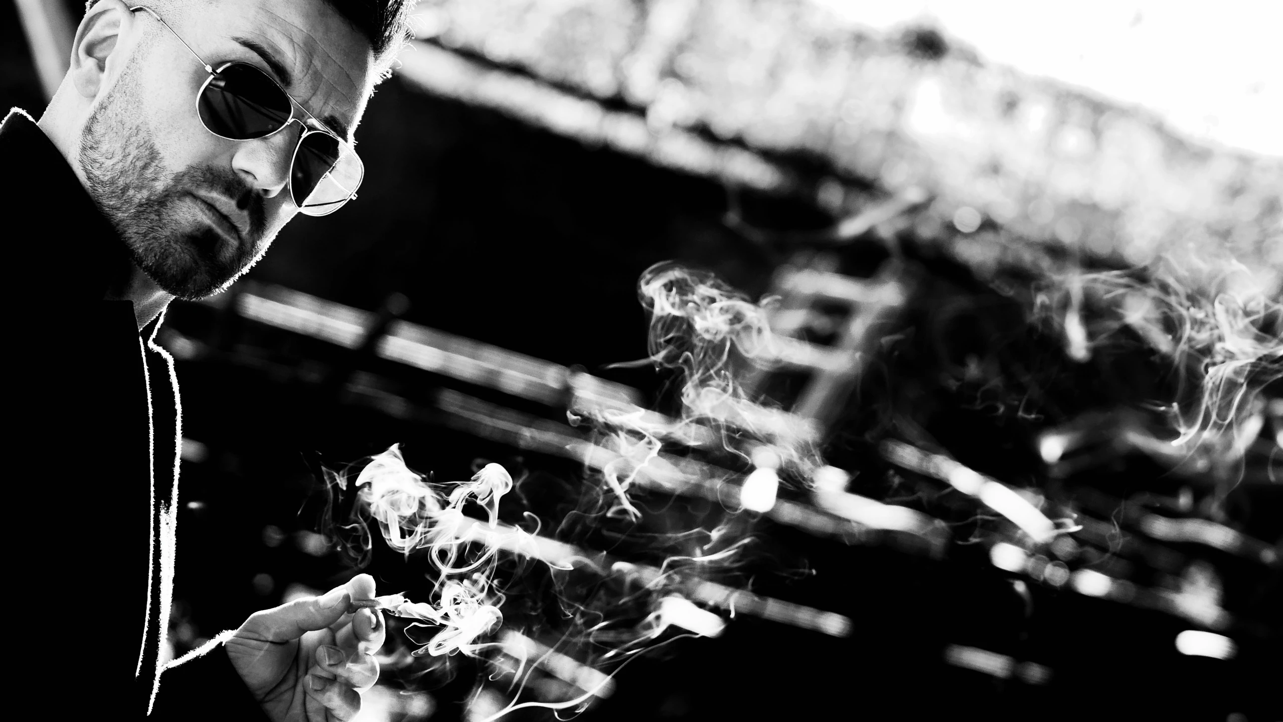 a man wearing sunglasses and holding a cigarette