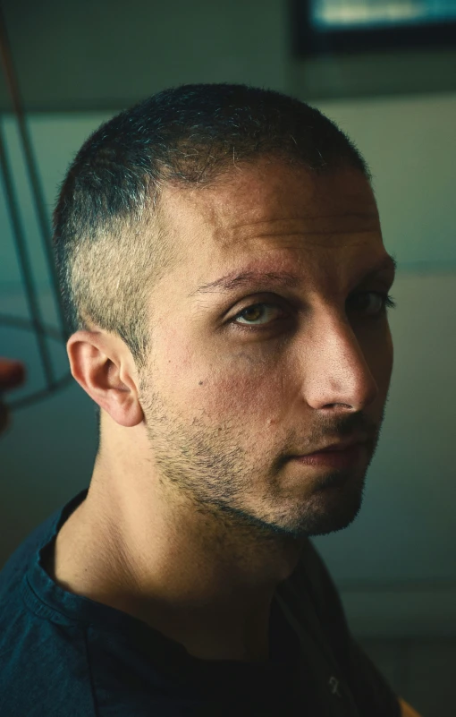 a man with a dark hair and black shirt looking away from the camera