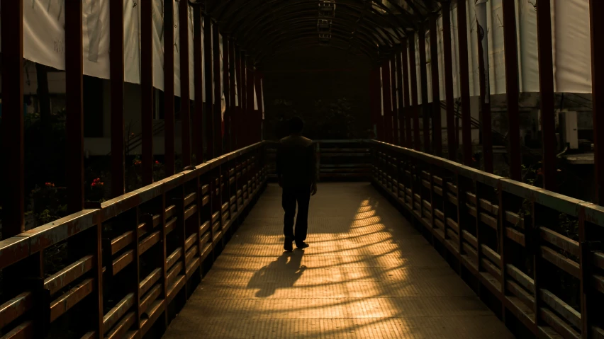 a man walks across a covered walkway in a train station