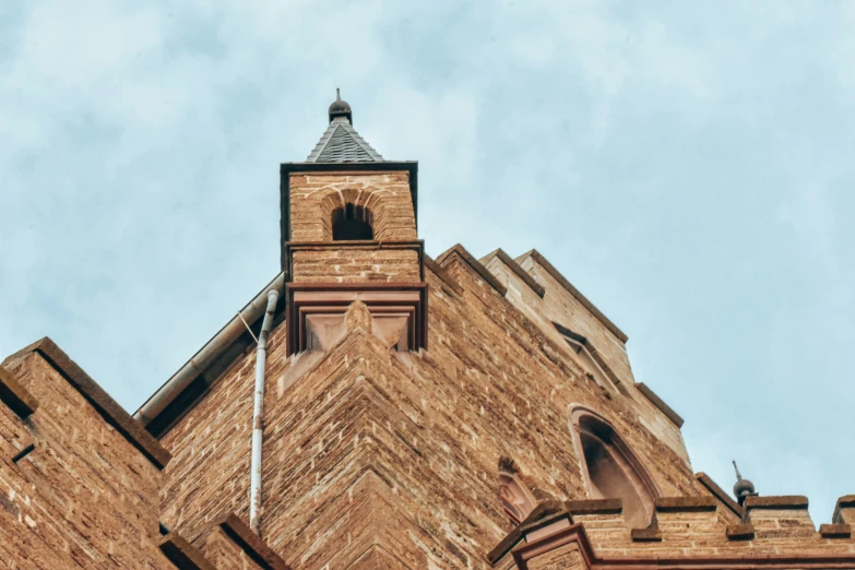 a tall brick building with a clock and weather vane