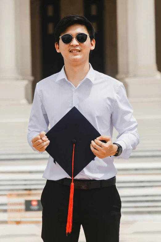 man with sunglasses on while he is holding up a book