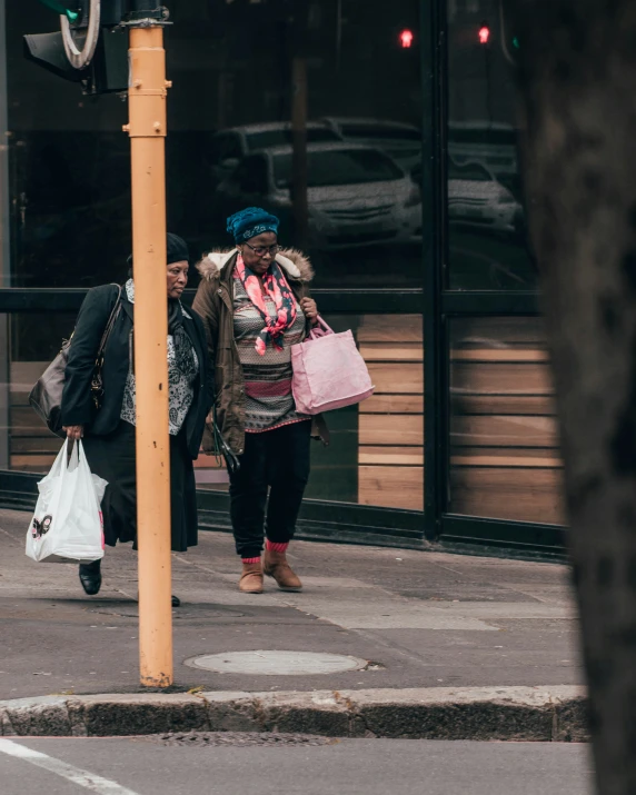 the woman has bags walking down the sidewalk