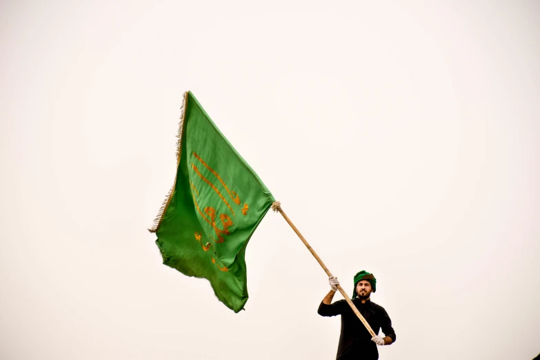 a man holding a green flag with writing