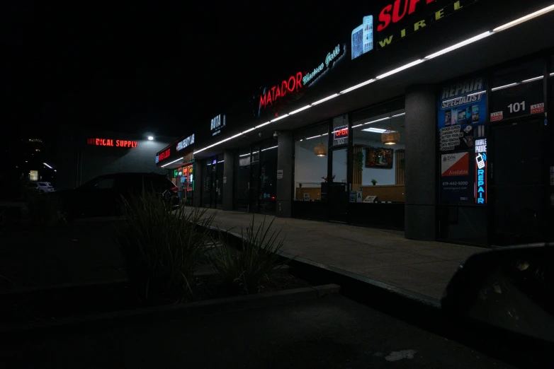 the sidewalk outside of a store lit up at night