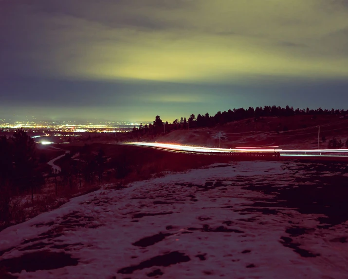 cars moving along a road at night with lights in the distance