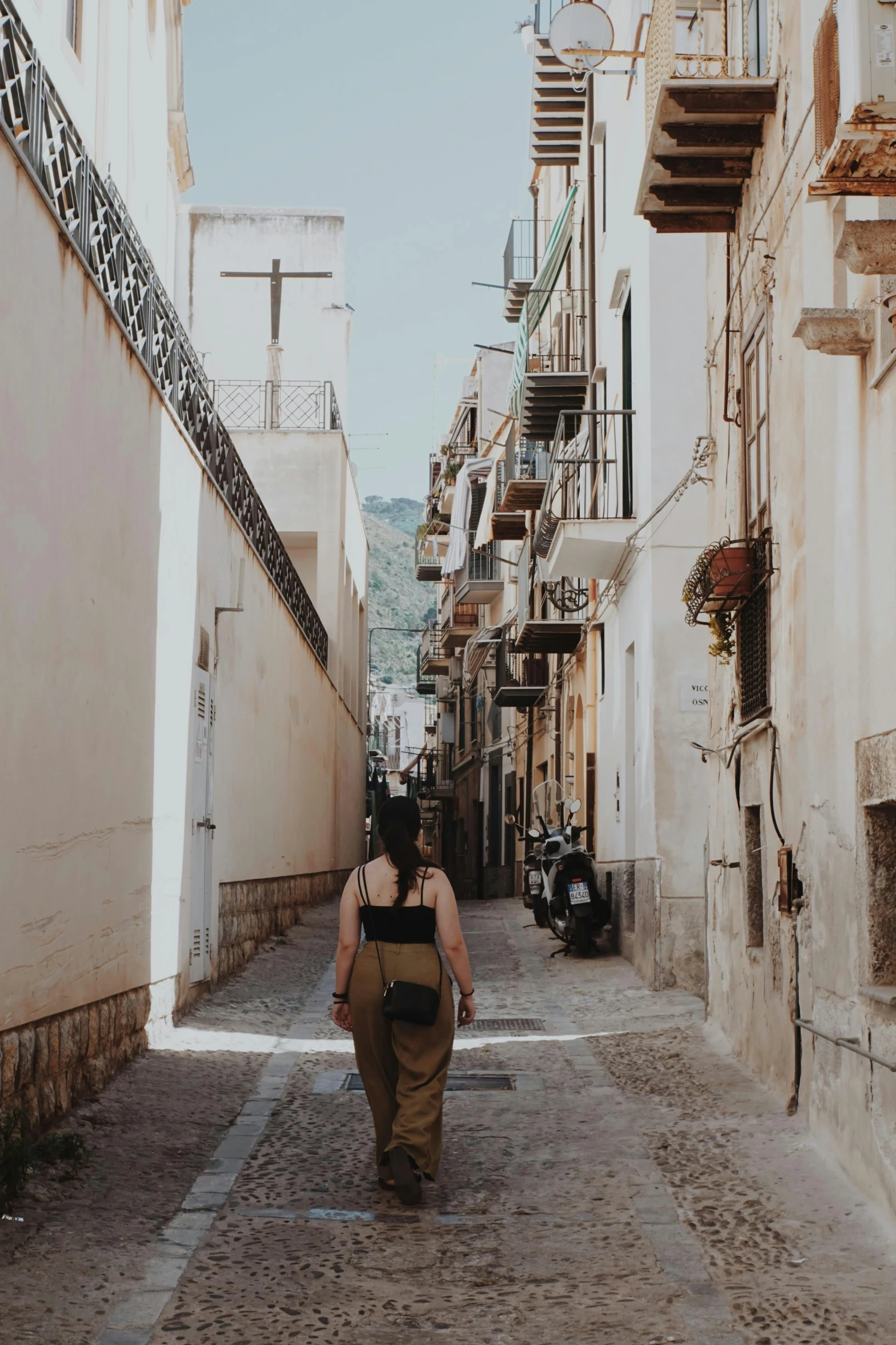 a woman walking in an alley way between two buildings