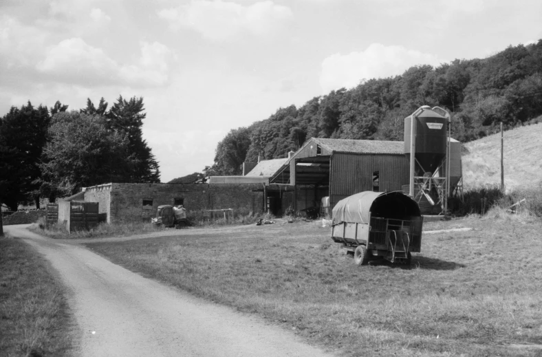 a black and white pograph shows a farm with a row of old barns