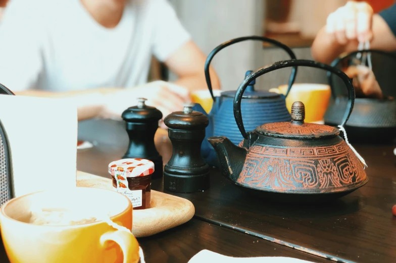 two cups, one teapot and the other is sitting on a table