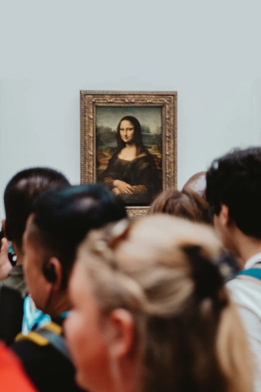 a crowd of people standing around a painting