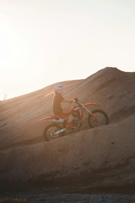 a person riding on a dirt bike on a dirt hill