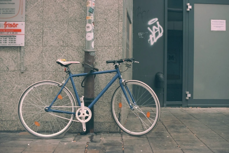 bicycle leaning against a street post with graffiti