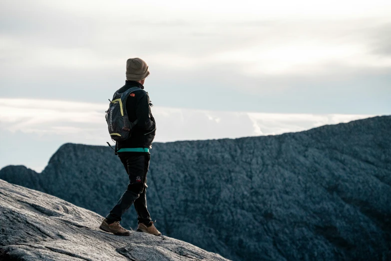 a man standing on top of a cliff with a backpack