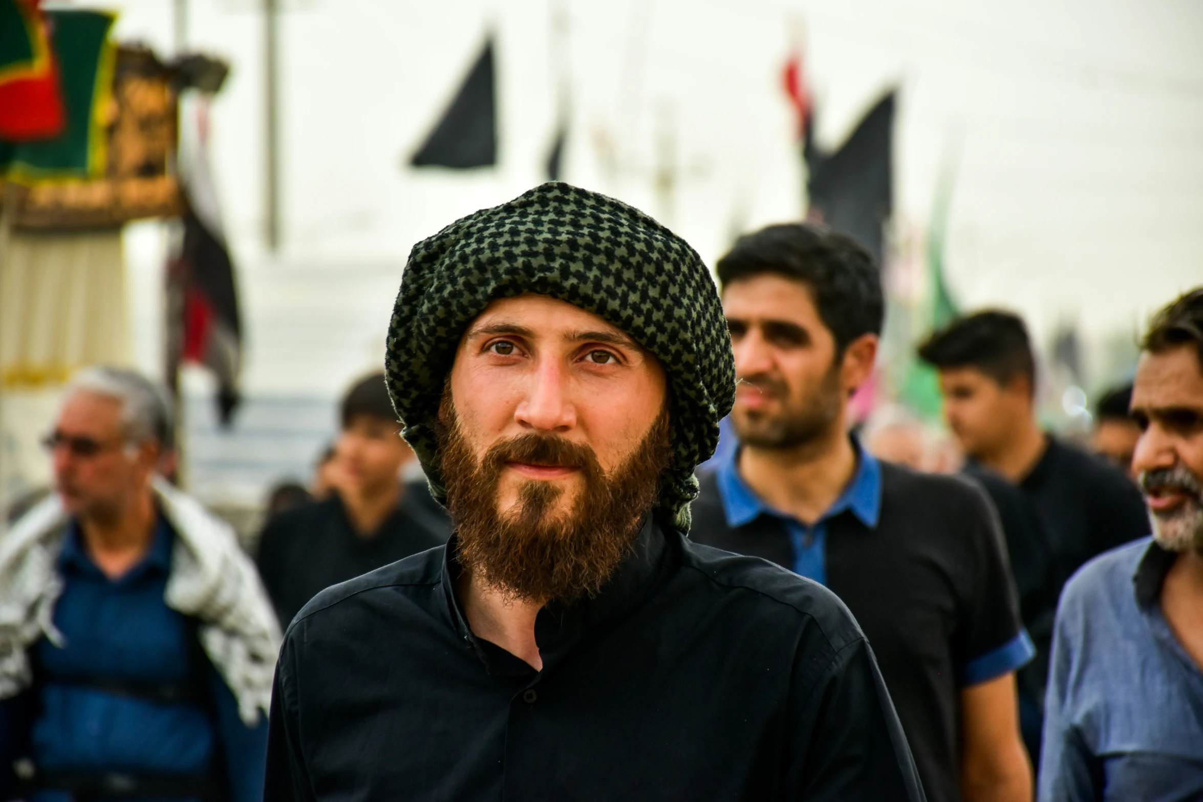 a man with a beard and black shirt walking around in a crowd