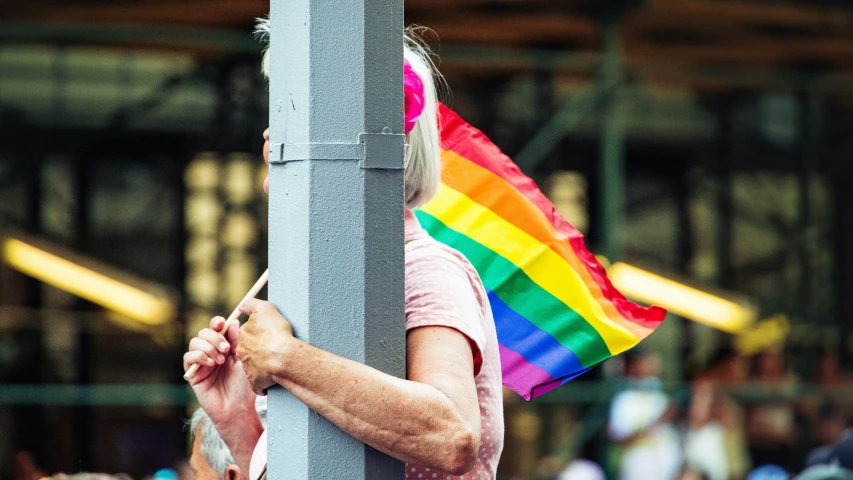 a woman is holding a rainbow flag around a pole