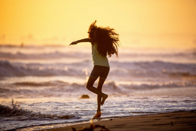 a woman running in the water on a beach at sunset