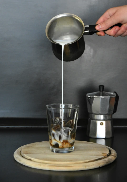 a person pouring soing into a glass on a counter