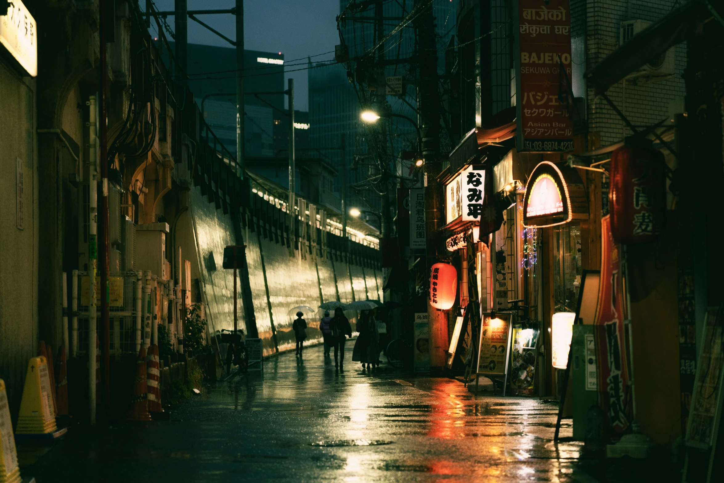 a city street with some people walking on the wet road