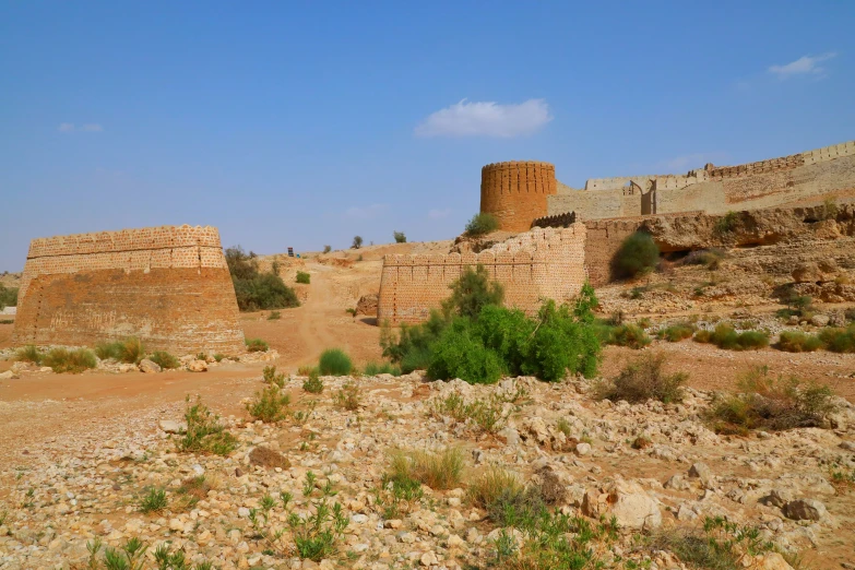 a large wall made of bricks next to a dirt road