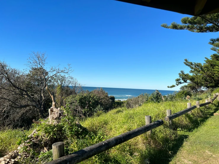 the ocean and land beyond a wooden fence