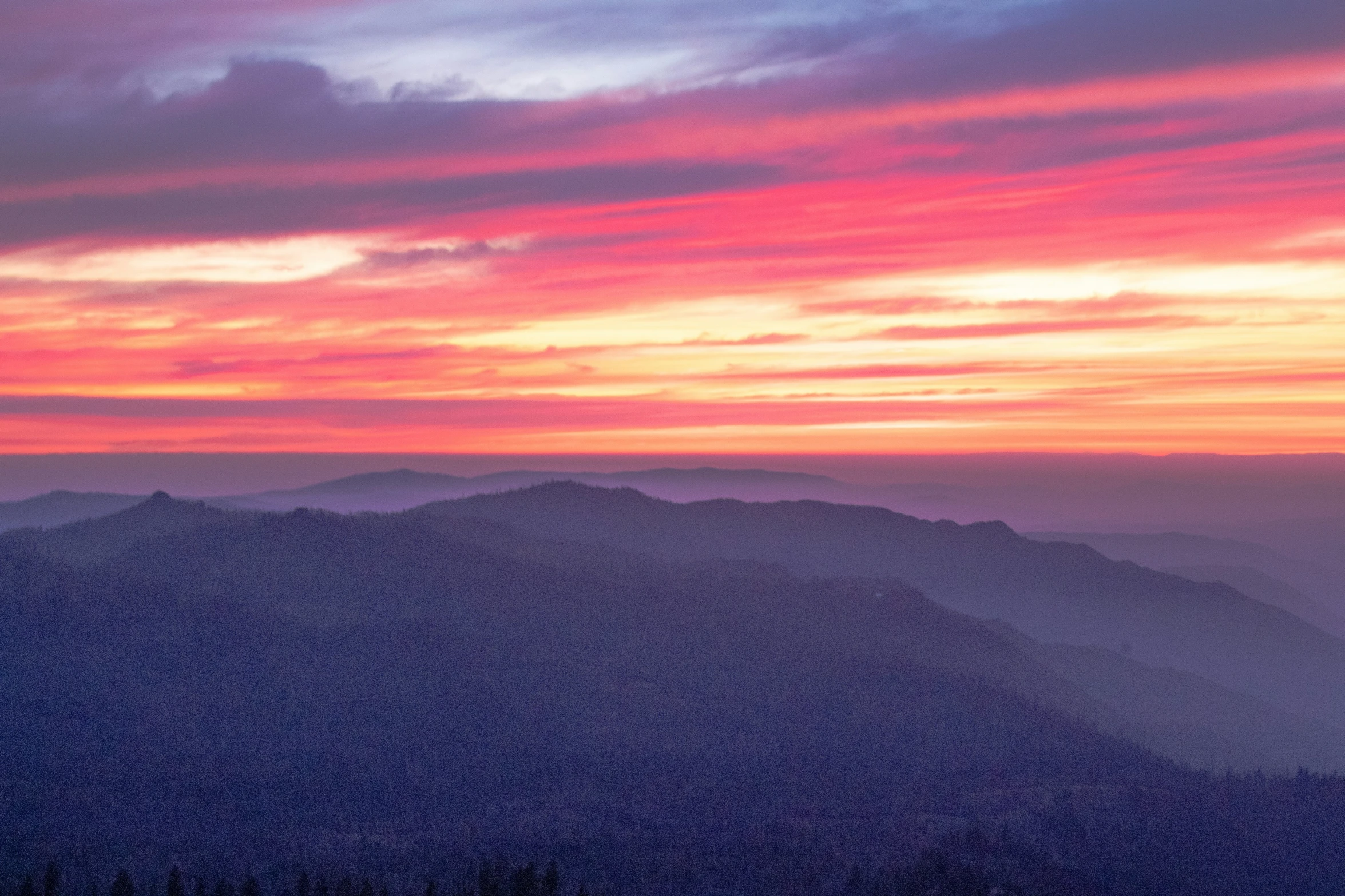 a colorful sunset above the clouds on top of a mountain