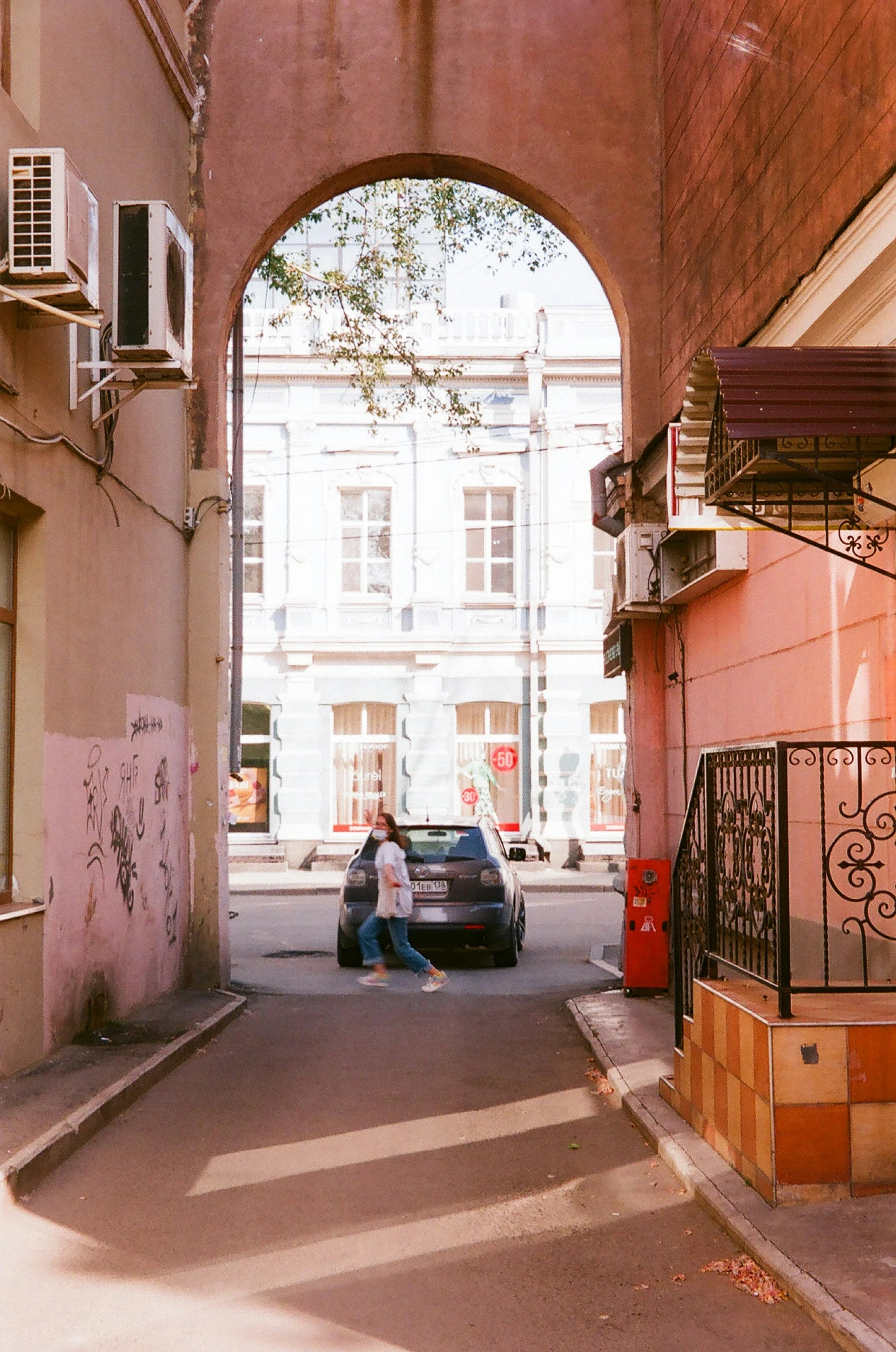 a car is parked by an archway in the alley way