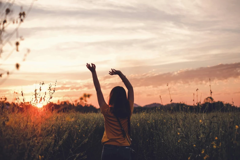 a girl raises her arms with her hands in the air