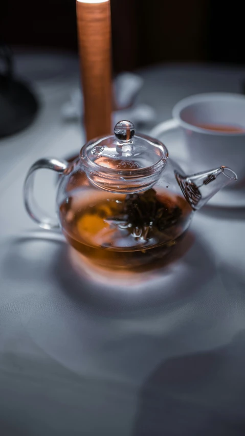a teapot containing a green tea with a teaspoon sitting on it