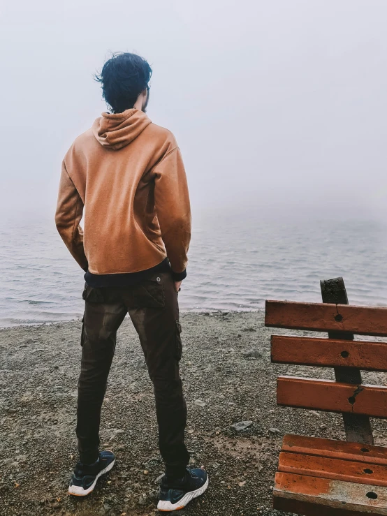 a man in a jacket is standing near a bench