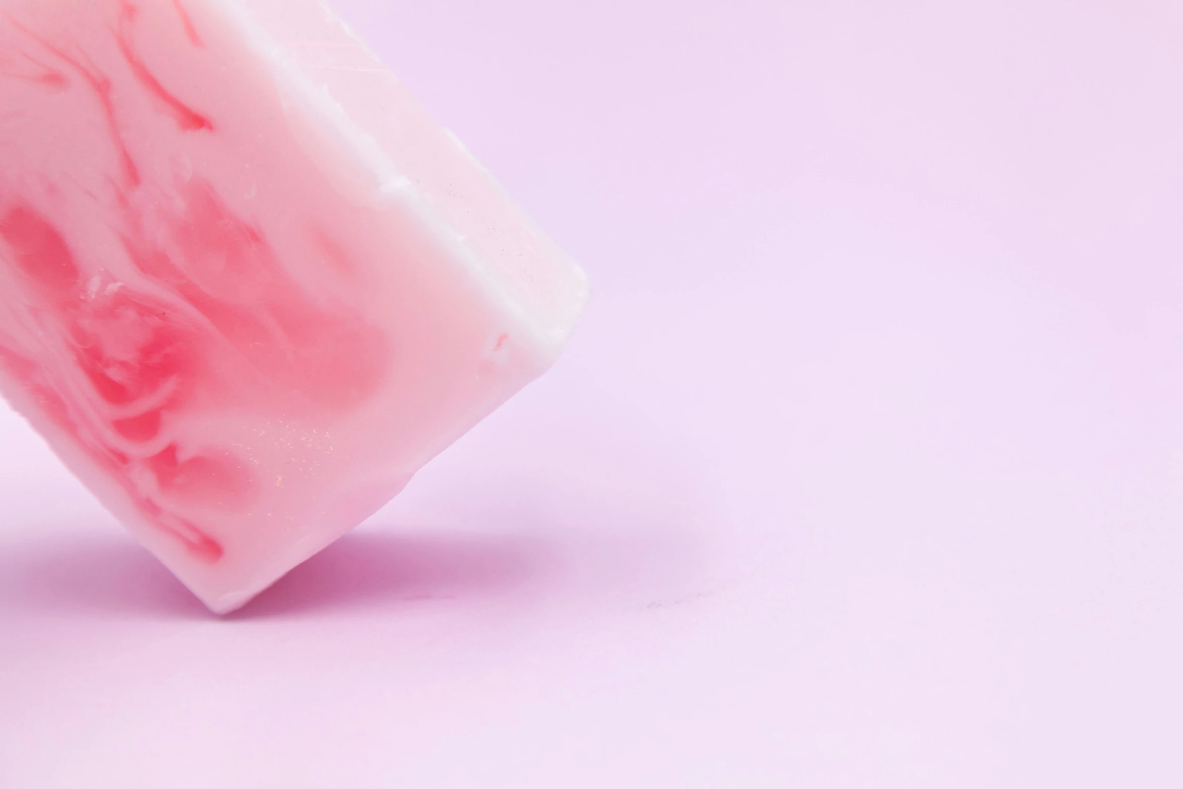 an unidentifiable bar of soap on top of a pink surface