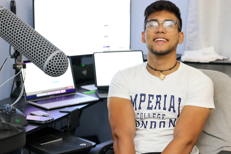 a man in a recording studio sitting with his arms crossed while holding a microphone