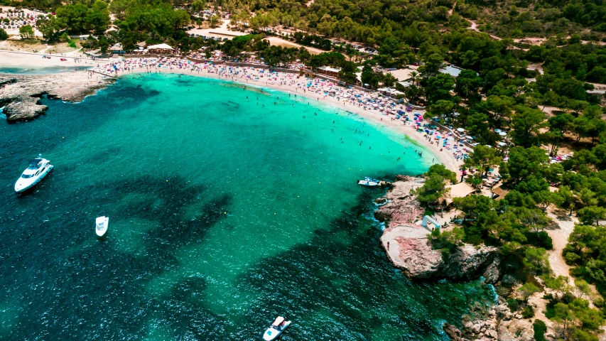 a beautiful beach is crowded with many boats