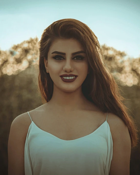 a girl smiling wearing white clothing with long brown hair