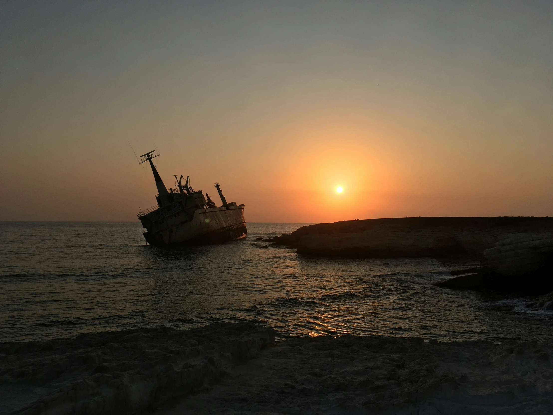 the silhouette of two ships off of a coast