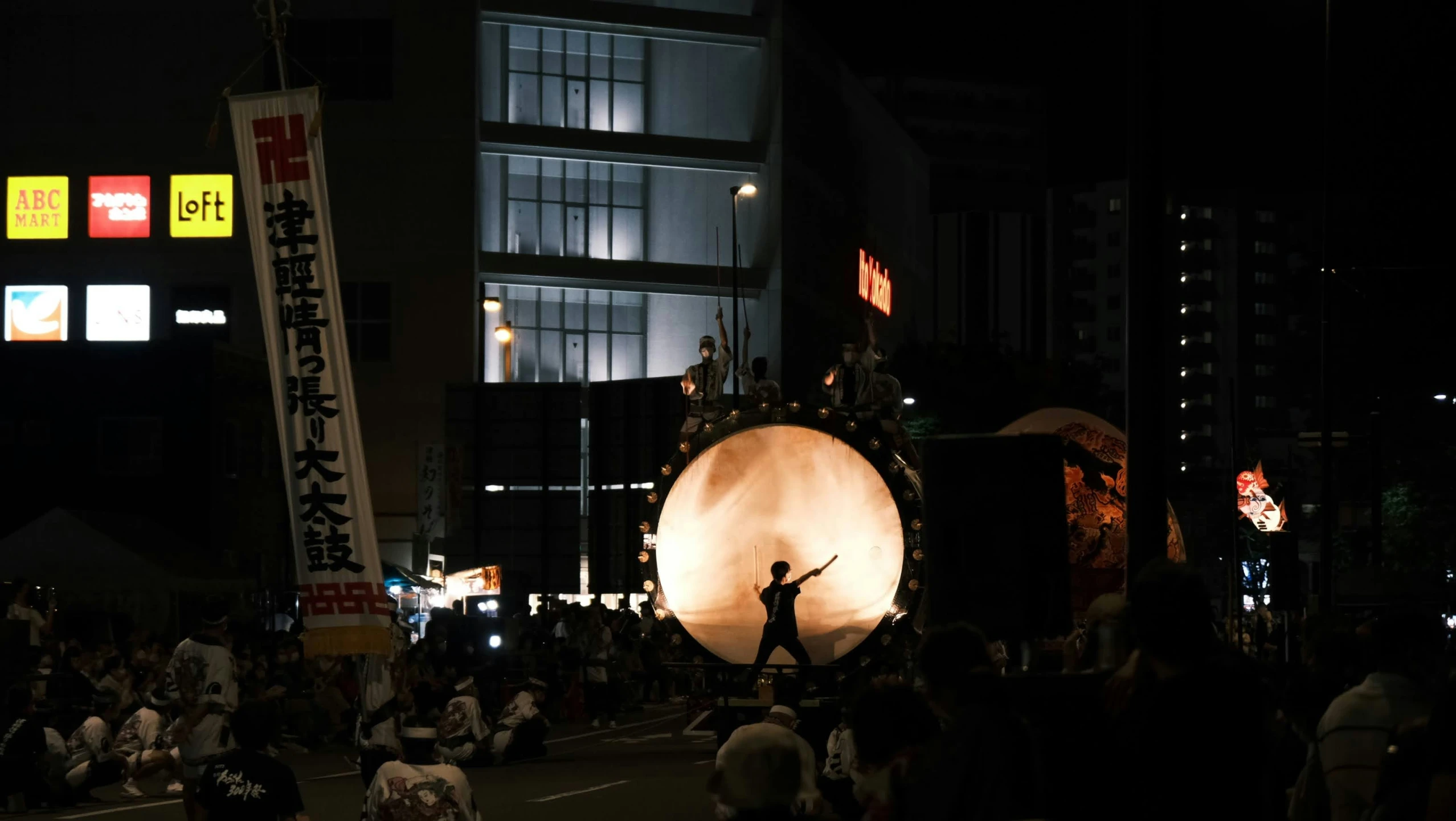 a parade with several performers on stilts on a city street at night