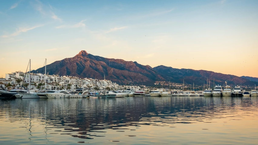 boats in the water near a mountain at sunset