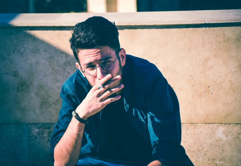 a man wearing glasses sitting on a step